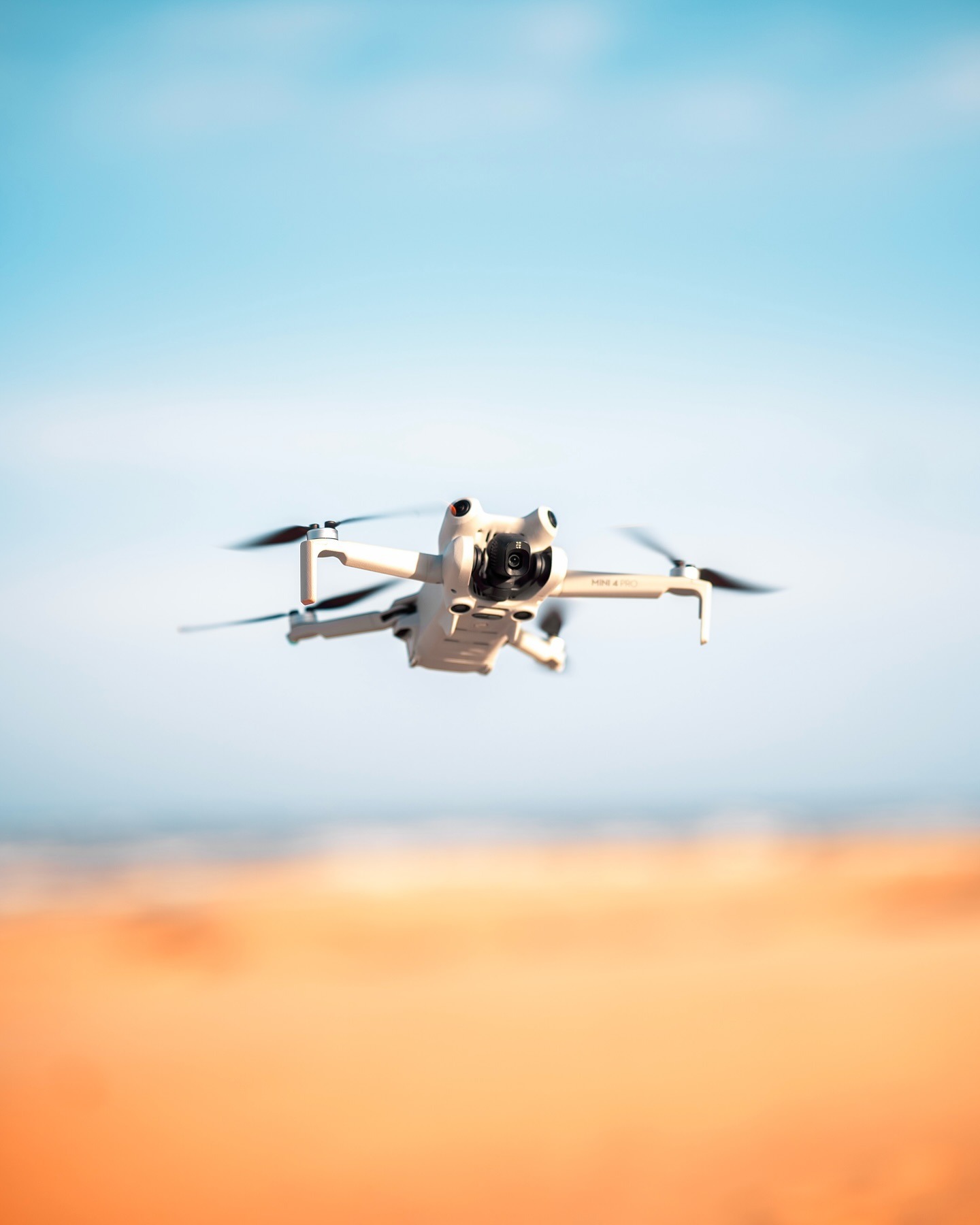 DJI Mini 4 Pro drone in flight over dunes